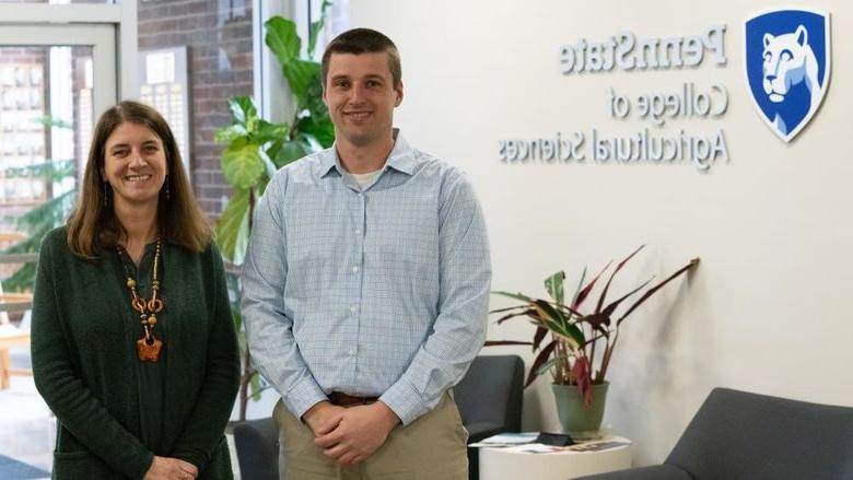 Two people stand in front of a wall that reads "Penn State College of Agricultural Sciences"